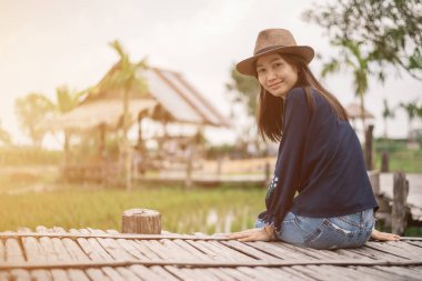 Tayland 'da pirinç çiftliğinde bambu masasında oturan mutlu Asyalı kadın..