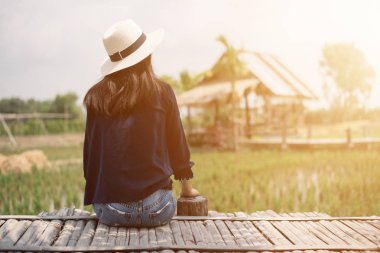Tayland 'da pirinç çiftliğinde bambu masasında oturan mutlu Asyalı kadın..