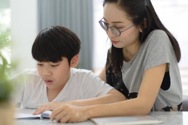 Asyalı kadın Asyalı çocuk masada evde ödev yardım.