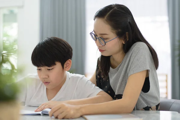 Asyalı kadın Asyalı çocuk masada evde ödev yardım.
