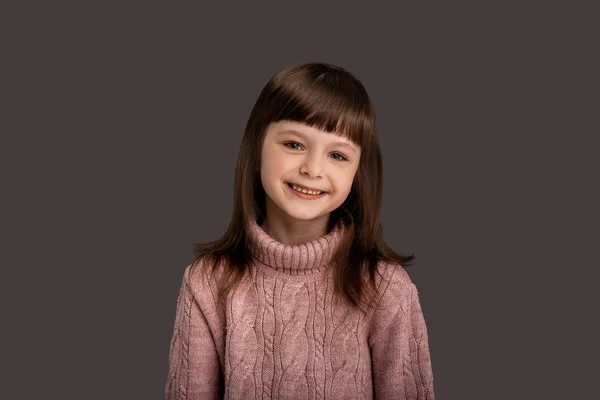 笑容可亲的漂亮小女孩穿着粉色毛衣 背景灰蒙蒙的 活跃而美丽的童年时光 快乐的表达 小女孩高加索模型 可爱的 迷人的脸 孩子的脸 生活方式概念 — 图库照片