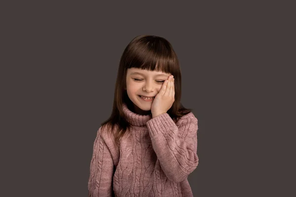 笑容可亲的漂亮小女孩穿着粉色毛衣 背景灰蒙蒙的 活跃而美丽的童年时光 快乐的表达 棕榈脸 迷人的脸 孩子的脸 生活方式概念 — 图库照片