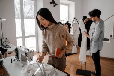 Yeni bir koleksiyon geliştirme sürecinde modern bir yaratıcı iş, kendi giyim tarzı ve sergi salonu. Tasarım, dikiş ve kesim stüdyosu, tasarımcı giysileri, imalat