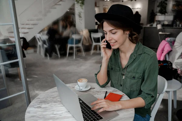 経営者の女性は通りのカフェで屋内で働き コーヒーを飲み 電話をかける フリーランス 起業家 カウリングスペースでの仕事 公共の場所 現代人のライフスタイル ビジネスオンラインコンセプト — ストック写真