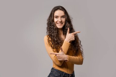 İki seçenek arasındaki seçim. Sağ mı sol mu? Sarı giyinmiş, beyaz arka plandaki gülümseyen kız farklı yönleri işaret ediyor. İnsanlar duygularını ifade eder.