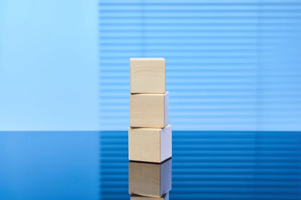 青い背景に3つの木製の立方体が重なり合って配置されています またはラベルのための無料スペース インフォグラフィックのレイアウト — ストック写真