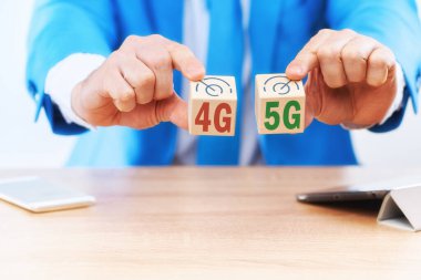 İş konsepti 4G ve 5G iletişim standartlarını seçmek ve karşılaştırmak. İş adamı her küpte sırasıyla 4G nano 5G yazan küpleri tutuyor..