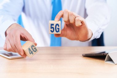 İş konsepti 4G ve 5G iletişim standartlarını seçmek ve karşılaştırmak. İş adamı her küpte sırasıyla 4G nano 5G yazan küpleri tutuyor..
