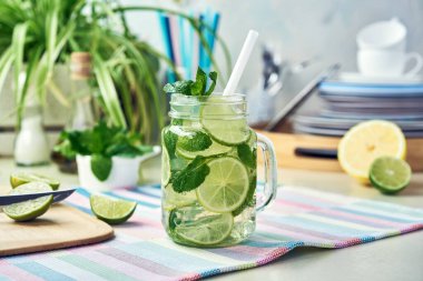 Bir bardak ev yapımı limon, limon ve naneli limonata ahşap yemek masasında duruyor. Soğuk, ferahlatıcı yaz limonatası ya da mojito..