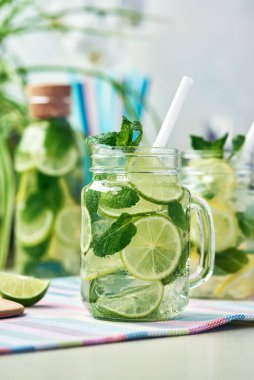Bir bardak ev yapımı limon, limon ve naneli limonata ahşap yemek masasında duruyor. Soğuk, ferahlatıcı yaz limonatası ya da mojito..