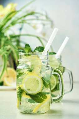 İki bardak ev yapımı limon, limon ve naneli limonata ahşap yemek masasında oturur. Soğuk, ferahlatıcı yaz limonatası ya da mojito..