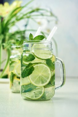 İki bardak ev yapımı limon, limon ve naneli limonata ahşap yemek masasında oturur. Soğuk, ferahlatıcı yaz limonatası ya da mojito..