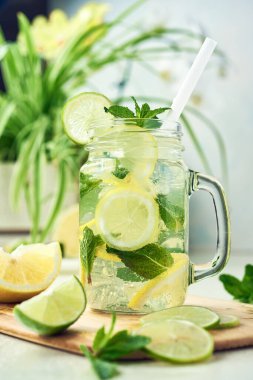 Bir bardak ev yapımı limon, limon ve naneli limonata ahşap yemek masasında duruyor. Soğuk, ferahlatıcı yaz limonatası ya da mojito..