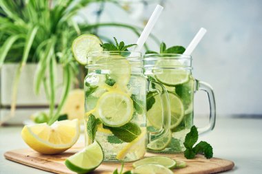 İki bardak ev yapımı limon, limon ve naneli limonata ahşap yemek masasında oturur. Soğuk, ferahlatıcı yaz limonatası ya da mojito..