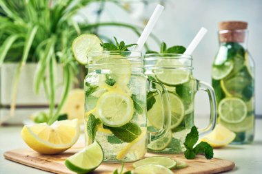 İki bardak ve bir şişe ev yapımı limon, limon ve naneli limonata ahşap yemek masasında oturur. Soğuk, ferahlatıcı yaz limonatası ya da mojito..