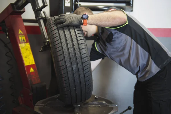 car mechanic using a machine to balance the wheel of a car