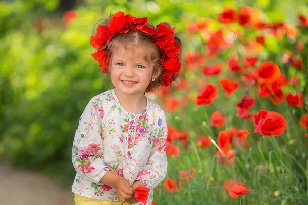 Retrato de una hermosa niña divirtiéndose en el campo de las flores de amapola roja en primavera. —  Fotos de Stock