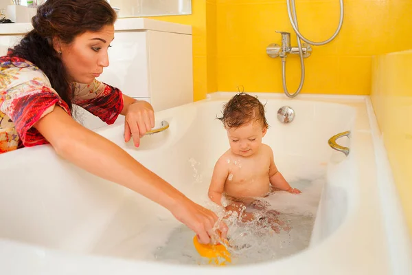 Smiling kid with foam and soap bubbles in bathroom.