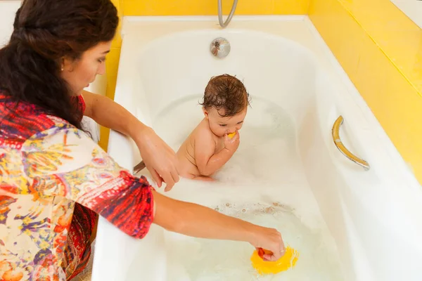 Smiling kid with foam and soap bubbles in bathroom.