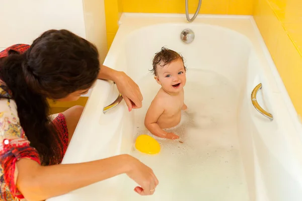 Smiling kid with foam and soap bubbles in bathroom.
