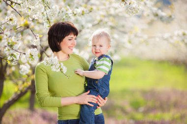 Mutlu kadın ve çocuk çiçek açan bahar bahçesinde.