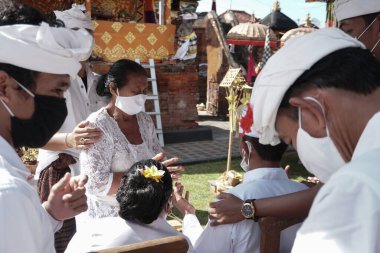 DENPASAR / BALI-MAY 7 2020: Bir kadın covid-19 salgını patlak verdiğinde Bali 'deki bir Hindu dini ayini sırasında transa geçti. Töreni sağlık protokolüyle yapıyorlar. Korunmak için maske kullanıyorlar.