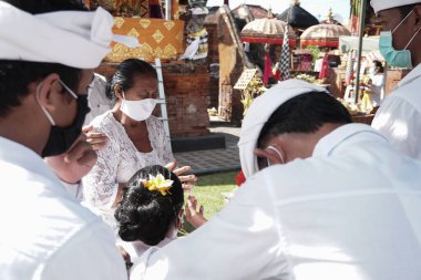 DENPASAR / BALI-MAY 7 2020: Bir kadın covid-19 salgını patlak verdiğinde Bali 'deki bir Hindu dini ayini sırasında transa geçti. Töreni sağlık protokolüyle yapıyorlar. Korunmak için maske kullanıyorlar.