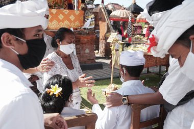DENPASAR / BALI-MAY 7 2020: Bir kadın covid-19 salgını patlak verdiğinde Bali 'deki bir Hindu dini ayini sırasında transa geçti. Töreni sağlık protokolüyle yapıyorlar. Korunmak için maske kullanıyorlar.