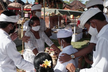 DENPASAR / BALI-MAY 7 2020: Bir kadın covid-19 salgını patlak verdiğinde Bali 'deki bir Hindu dini ayini sırasında transa geçti. Töreni sağlık protokolüyle yapıyorlar. Korunmak için maske kullanıyorlar.