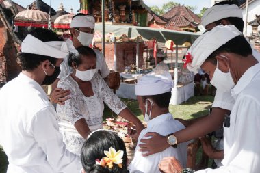 DENPASAR / BALI-MAY 7 2020: Bir kadın covid-19 salgını patlak verdiğinde Bali 'deki bir Hindu dini ayini sırasında transa geçti. Töreni sağlık protokolüyle yapıyorlar. Korunmak için maske kullanıyorlar.