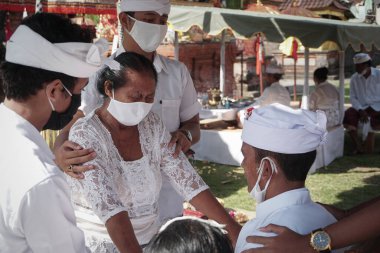 DENPASAR / BALI-MAY 7 2020: Bir kadın covid-19 salgını patlak verdiğinde Bali 'deki bir Hindu dini ayini sırasında transa geçti. Töreni sağlık protokolüyle yapıyorlar. Korunmak için maske kullanıyorlar.