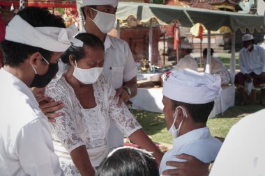 DENPASAR / BALI-MAY 7 2020: Bir kadın covid-19 salgını patlak verdiğinde Bali 'deki bir Hindu dini ayini sırasında transa geçti. Töreni sağlık protokolüyle yapıyorlar. Korunmak için maske kullanıyorlar.