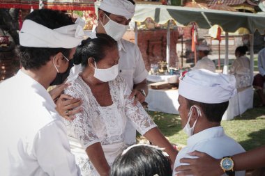 DENPASAR / BALI-MAY 7 2020: Bir kadın covid-19 salgını patlak verdiğinde Bali 'deki bir Hindu dini ayini sırasında transa geçti. Töreni sağlık protokolüyle yapıyorlar. Korunmak için maske kullanıyorlar.