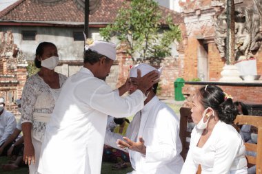 DENPASAR / BALI-MAY 7 2020: Salgın covid-19 patlak verdiğinde Bali 'de Hindu dini törenleri. Töreni yaparlar ve sağlık protokolüne uyarlar. Kendileri için hala maske kullandıklarını gördüm..