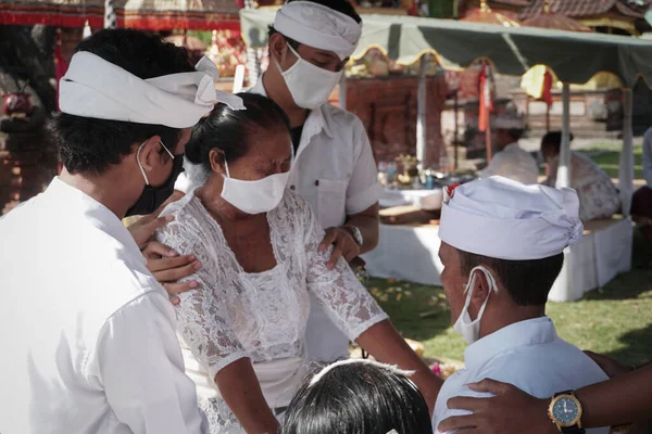 DENPASAR / BALI-MAY 7 2020: Bir kadın covid-19 salgını patlak verdiğinde Bali 'deki bir Hindu dini ayini sırasında transa geçti. Töreni sağlık protokolüyle yapıyorlar. Korunmak için maske kullanıyorlar.