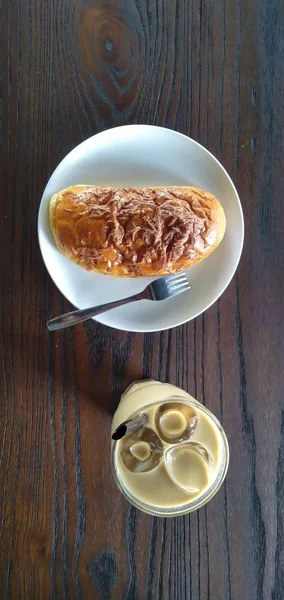 面包和冰镇咖啡拿铁放在木制桌角上方 — 图库照片