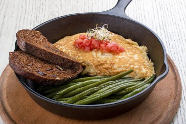 Beyaz arka planda bir tavada kahvaltı. Kuşkonmaz ve tost ile çırpılmış yumurta..