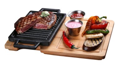 Tahta tepside biftek ve beyaz arka planda ızgara sebze.