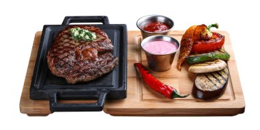 Tahta tepside biftek ve beyaz arka planda ızgara sebze.