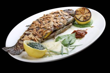 Çıtır badem kabuklu alabalık ve siyah arka planda fırında patates püresi.