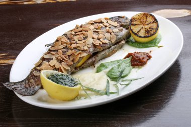 Çıtır badem kabuklu alabalık ve siyah arka planda fırında patates püresi.