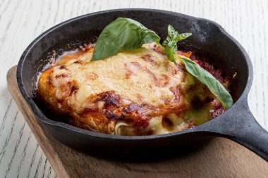 Tahtadaki dökme demir tavada lazanya. Geleneksel İtalyan yemeği