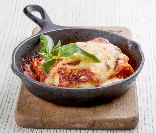 Lasagna in a cast iron pan on a wooden board. Traditional Italian dish — Stock Photo, Image