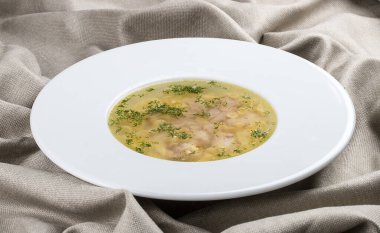 Tekstil arka planında beyaz tabakta tavuk çorbası.