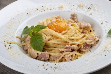 Tekstil arka planında beyaz tabakta spagetti Carbonara