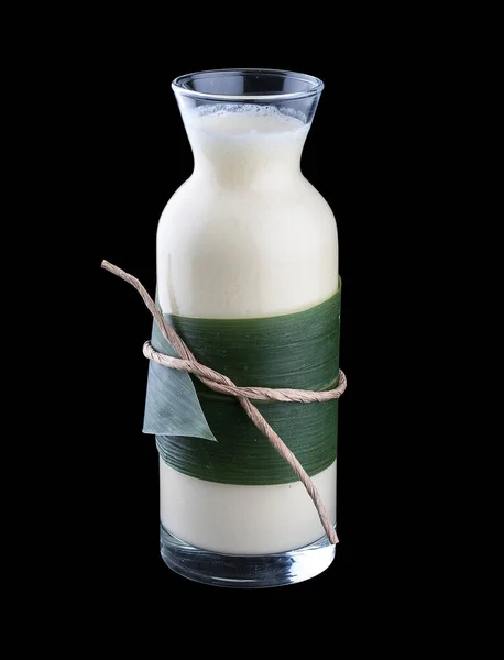 Milkshake with coconut milk. In a glass bottle on a dark background