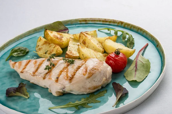 Grilled chicken fillet with fried potatoes. On light background