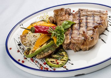 Izgara biftek ya da ızgara sebzeli biftek. Beyaz bir tabakta..