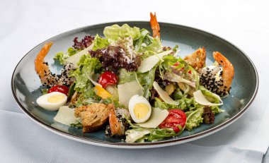 Parmesan peynirli ve karidesli taze sezar salatası. Dekoratif bir tabakta