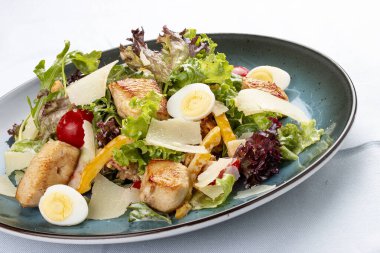 Sezar Salatası. Kızarmış tavuk göğsü, rendelenmiş parmesan peyniri ve salata soslu sos. Dekoratif bir tabakta